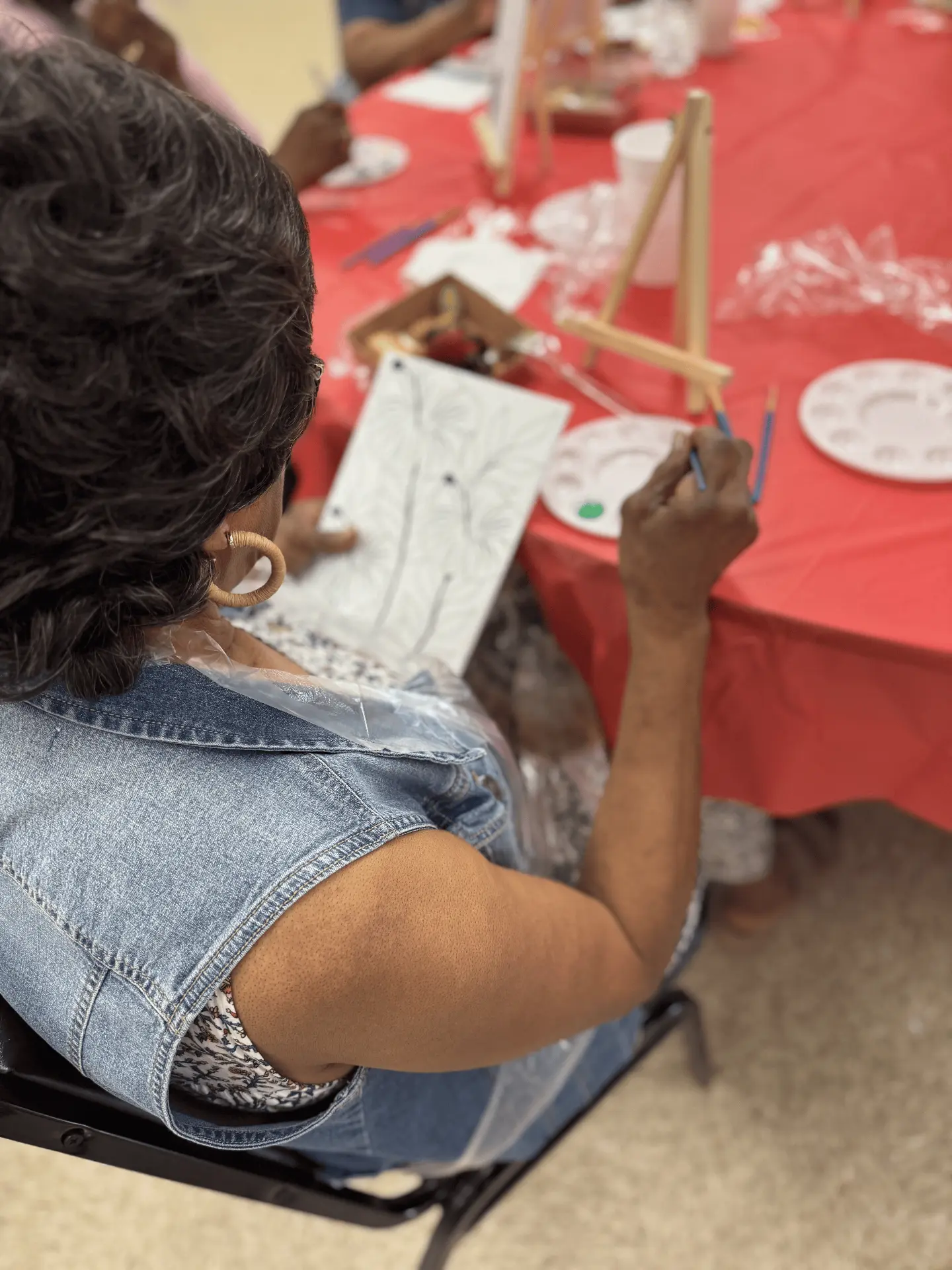 A woman painting at an easel during a Khesed Praise & Paint night